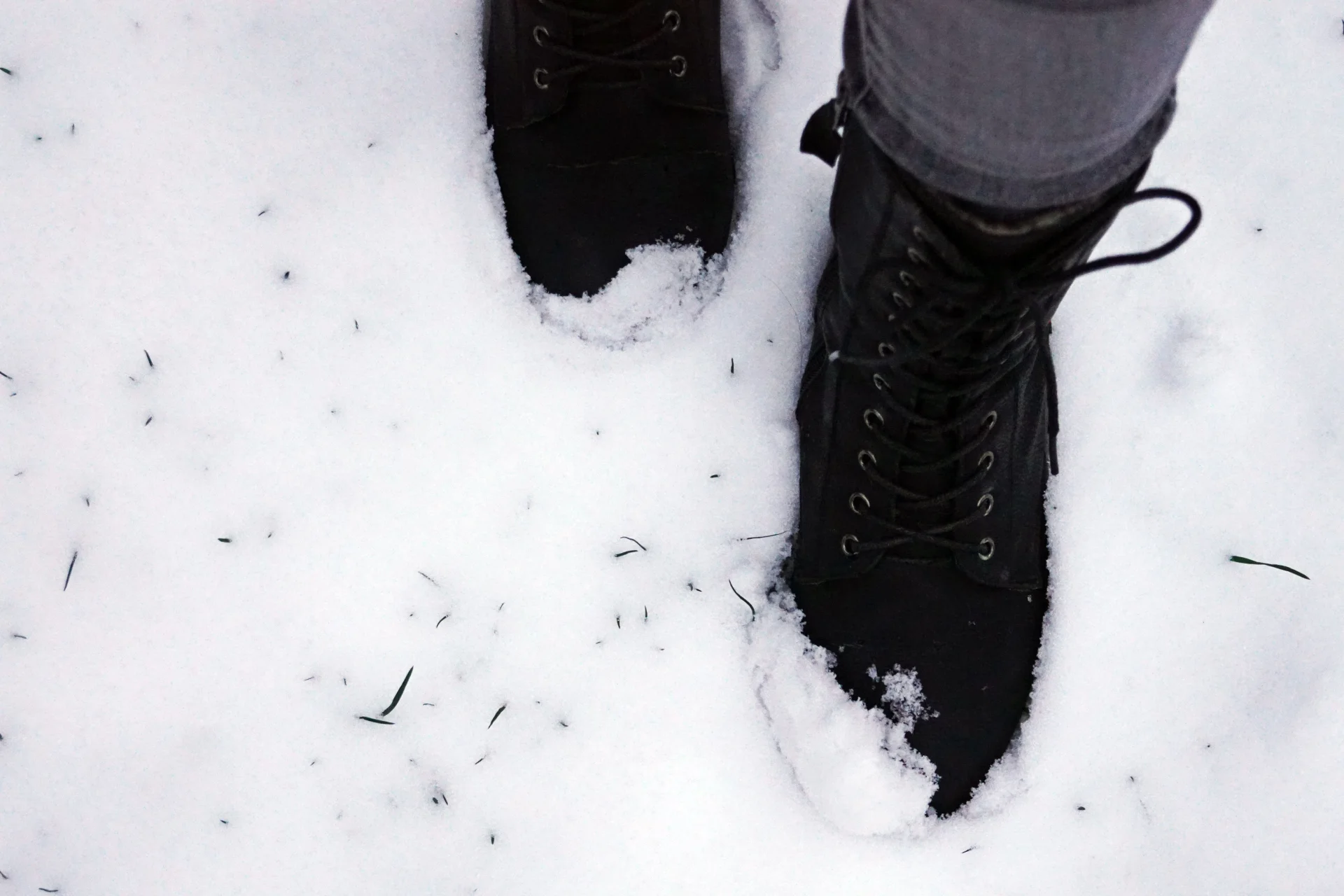 Czarne buty zostawiają ślad w świeżym śniegu, tworząc zimową scenę na zewnątrz.